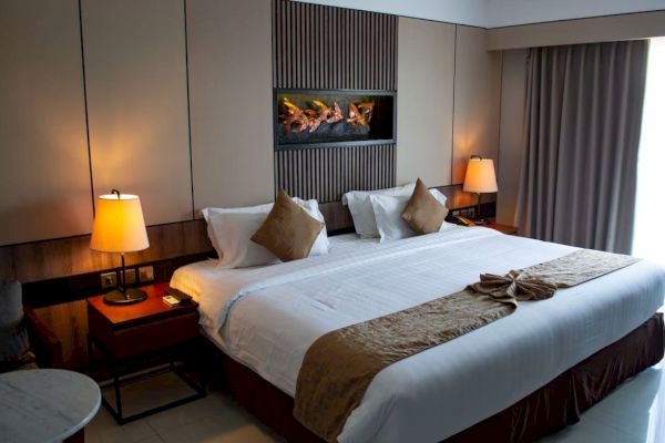 A hotel room featuring a king-sized bed, two bedside tables with lamps, and a decorative piece above the bed, creating a cozy ambiance.