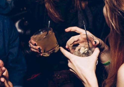 People are enjoying drinks and laughing together in a social setting, creating a lively and cheerful atmosphere.
