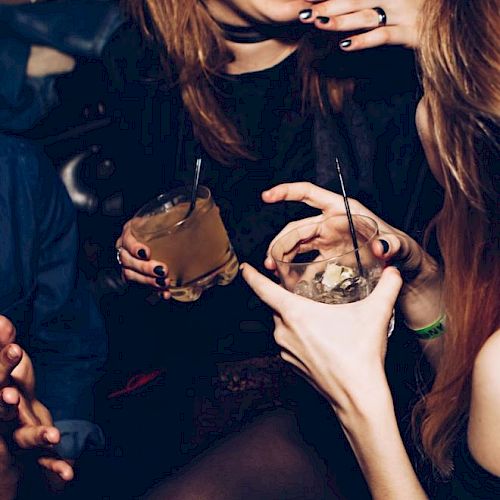 People are enjoying drinks and laughing together in a social setting, creating a lively and cheerful atmosphere.