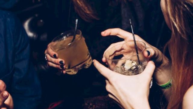 People are enjoying drinks and laughing together in a social setting, creating a lively and cheerful atmosphere.