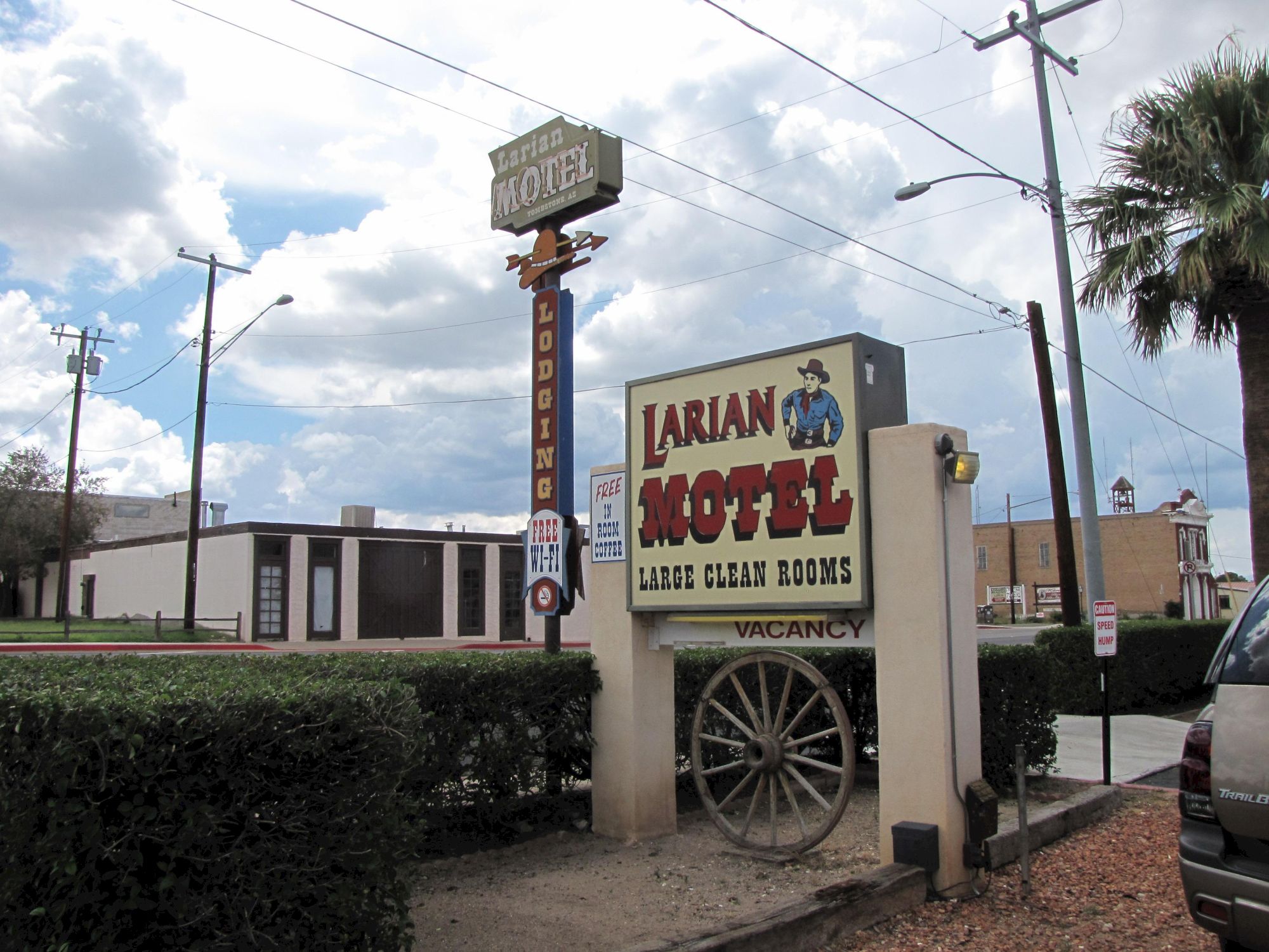The image shows a roadside sign for Larian Motel, advertising "Large Clean Rooms" and vacancy, with a wagon wheel decoration.