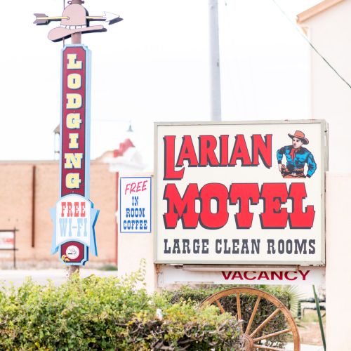 A vintage motel sign reads "Larian Motel" with "Large Clean Rooms" and "Vacancy" indicated, along with “Free WiFi” offered.